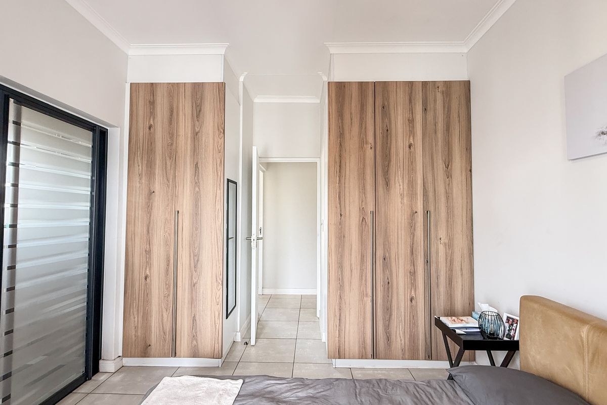A well-maintained bedroom featuring built-in wood-grain cabinetry, tiled flooring, and a sliding glass door providing access to an outdoor area.