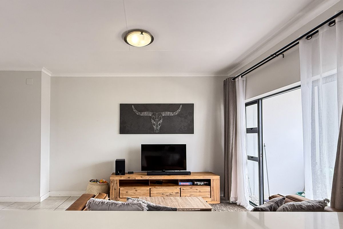 A bright and well-maintained living room featuring large sliding glass doors that provide access to an outdoor balcony area.