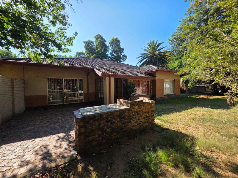 Rear view of the house featuring a paved patio area, brick low wall, and established garden surroundings.
