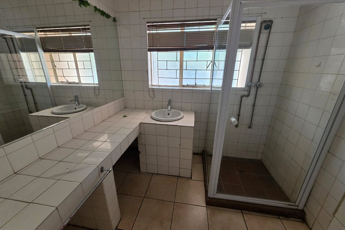 A dated bathroom featuring a tiled vanity with a drop-in basin, a separate shower enclosure, and full-height wall tiling.