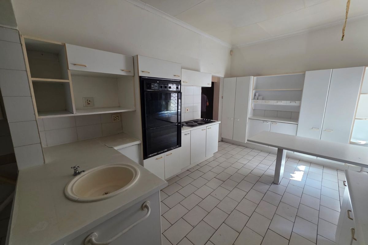 Spacious kitchen featuring built-in oven, hob, ample cabinetry, and tiled flooring, offering a functional layout ready for modern updates and renovation.