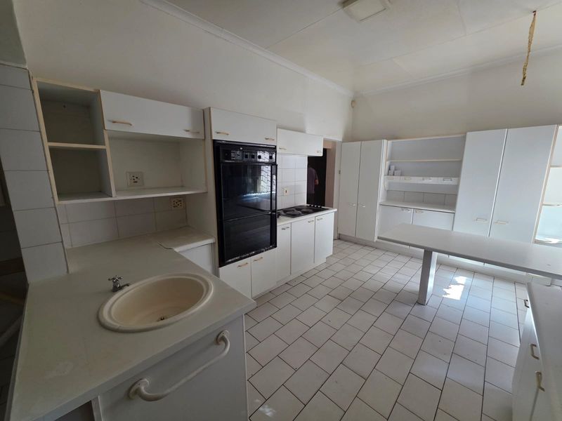 Spacious kitchen featuring built-in oven, hob, ample cabinetry, and tiled flooring, offering a functional layout ready for modern updates and renovation.