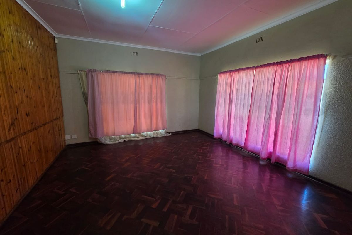 Spacious living area featuring traditional parquet flooring and timber wall paneling, offering a blank canvas for renovation and modern interior design updates.