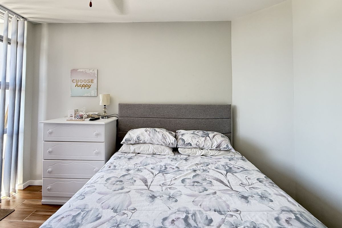 A bright bedroom featuring wood-look tile flooring and large windows that provide ample natural light.