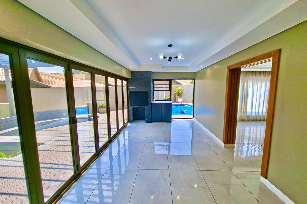 Spacious living area featuring large stacking glass doors opening to a pool deck, built-in fireplace, and polished tile flooring.