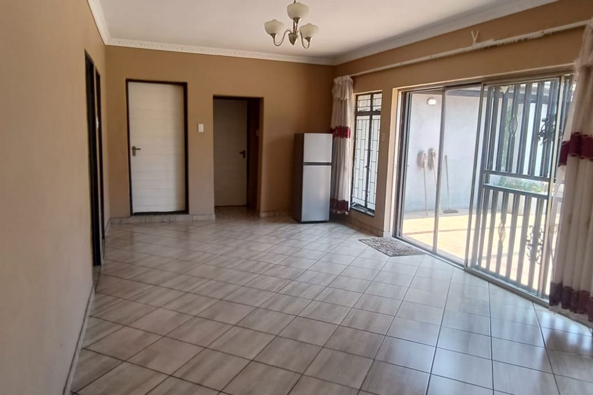A spacious living area featuring tiled flooring, large sliding glass doors with security gates, and direct access to the outdoor patio.
