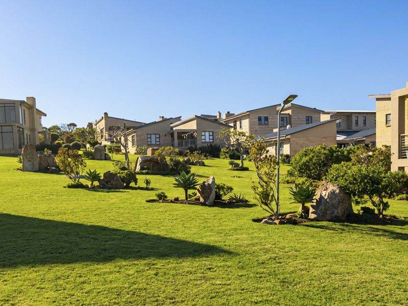 A well-maintained communal garden area featuring manicured lawns, decorative boulder rock formations, and established landscaping within a residential estate setting.