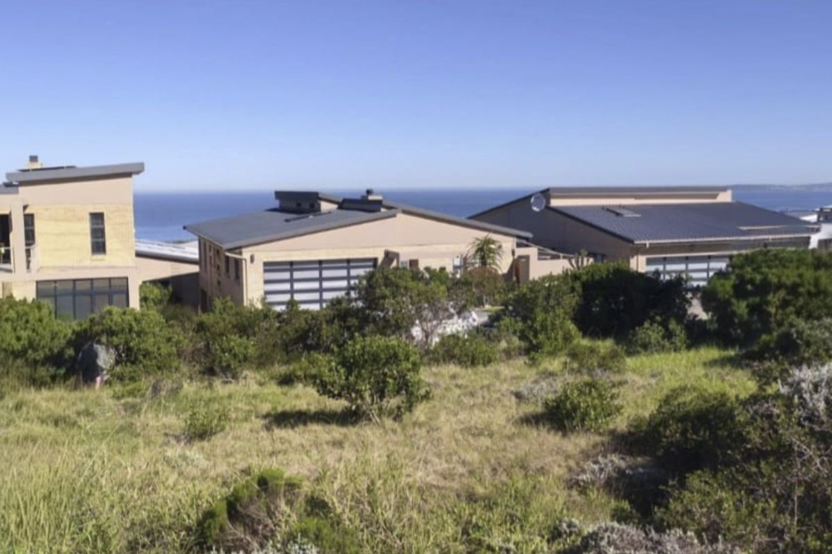 A view of modern residential buildings with pitched roofs and garage doors, set against a coastal landscape backdrop.