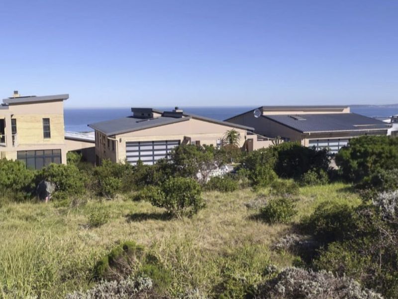 A view of modern residential buildings with pitched roofs and garage doors, set against a coastal landscape backdrop.