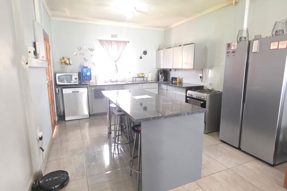 A functional kitchen featuring a central island, tiled flooring, and built-in cabinetry with integrated workspace.