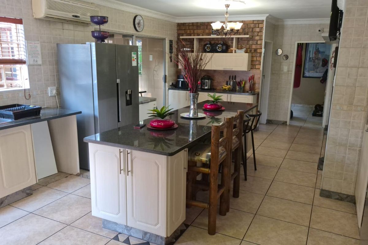 Spacious kitchen featuring a central island with granite countertops, tiled flooring, and built-in cabinetry, offering a functional layout for cooking and casual dining.