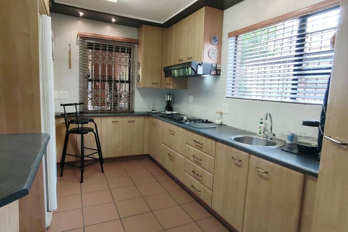 Functional kitchen featuring light wood cabinetry, dark countertops, tiled flooring, and integrated hob with extractor fan.