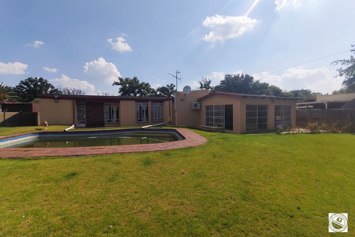 Rear view of the property featuring a swimming pool, expansive lawn, and direct access to the main dwelling.