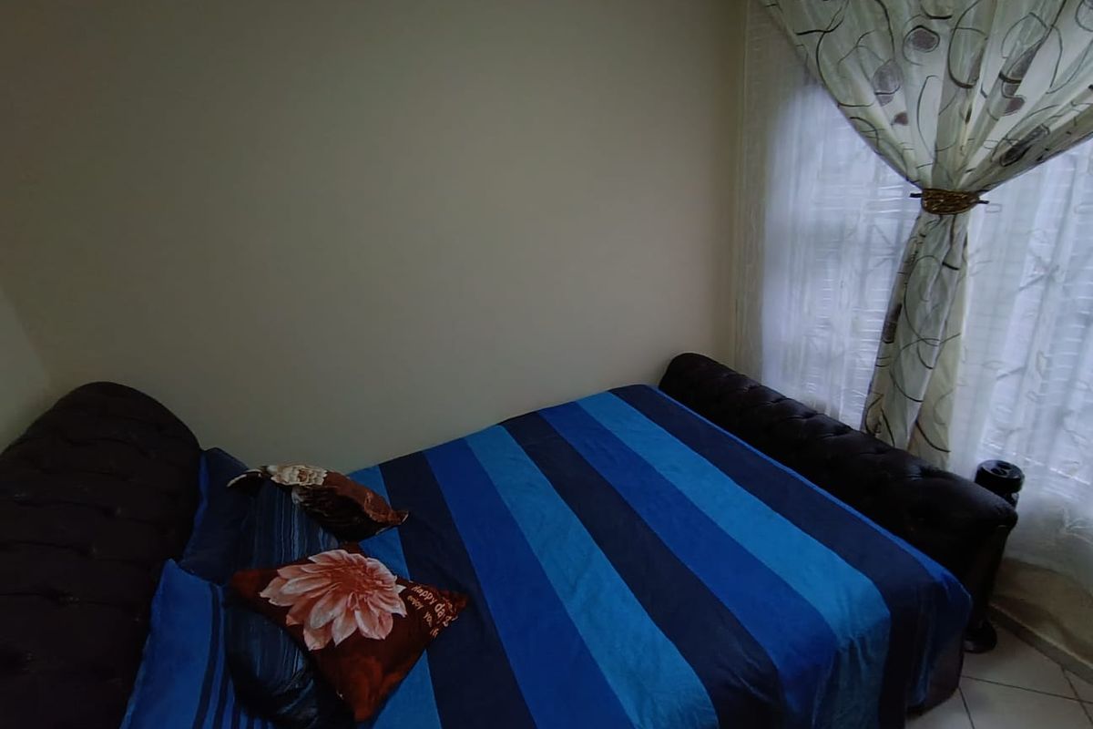 A standard bedroom featuring tiled flooring and a window with curtains.