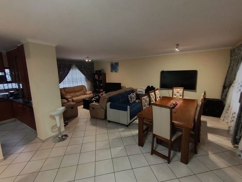 Spacious open-plan living and dining area featuring tiled flooring, integrated kitchen cabinetry, and a functional layout suitable for family living.