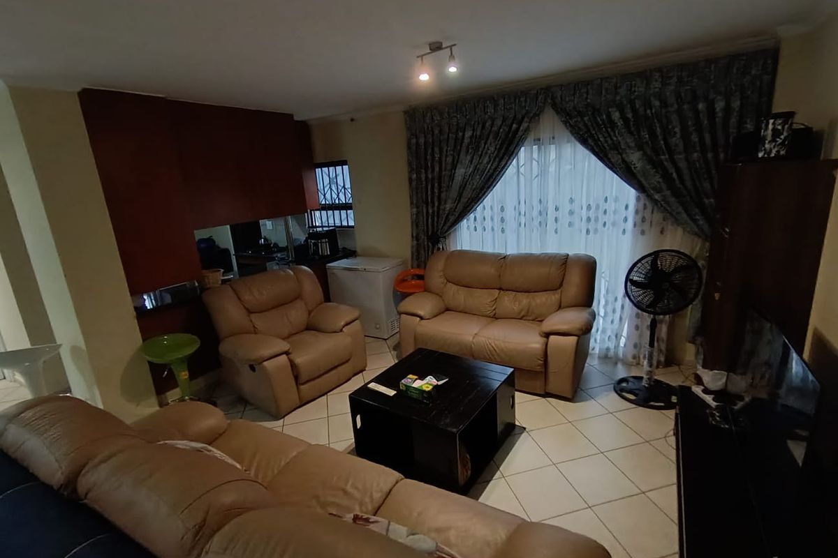 A living room featuring tiled flooring and a sliding glass door with curtains, including a built-in bar area.