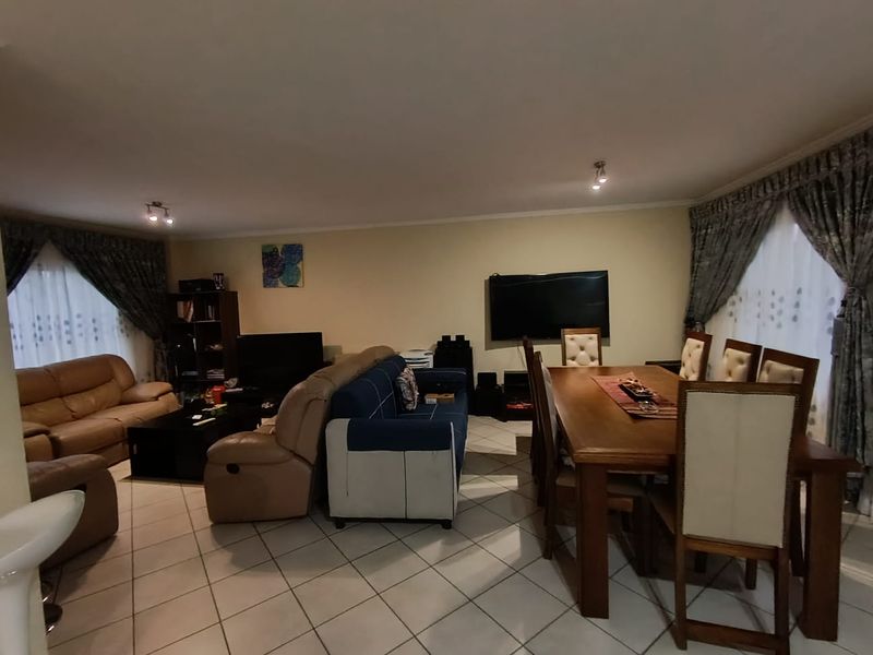 Spacious open-plan living and dining area featuring ceramic floor tiles and neutral wall finishes, providing a versatile layout for family living.