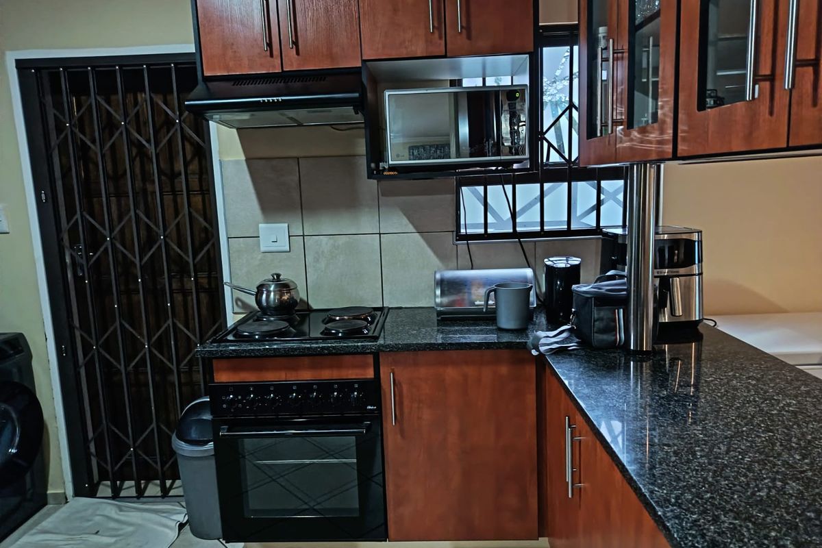 A functional kitchen featuring dark wood cabinetry, granite countertops, a built-in oven and stove, and a tiled backsplash.