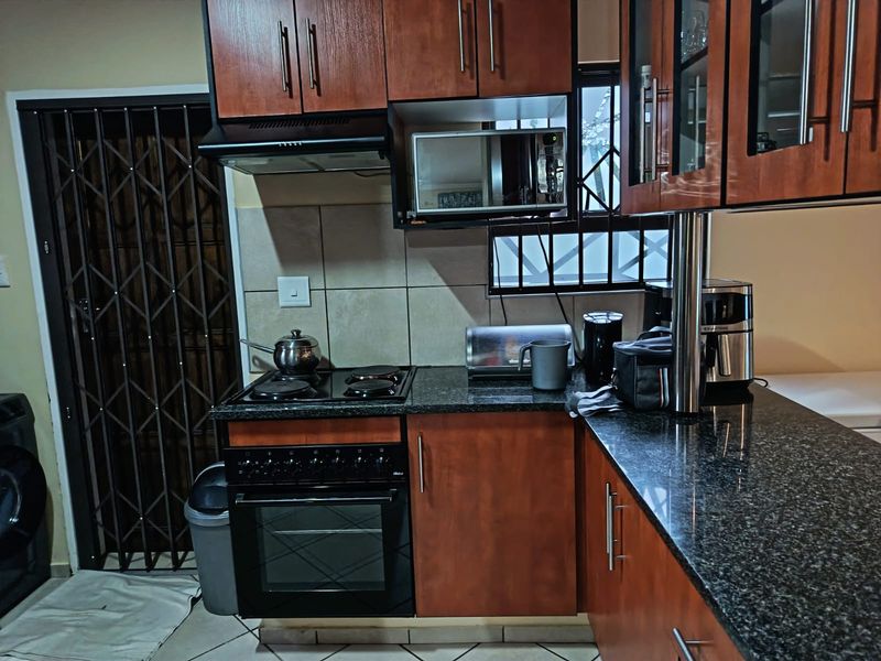 A functional kitchen featuring dark wood cabinetry, granite countertops, a built-in oven and stove, and a tiled backsplash.