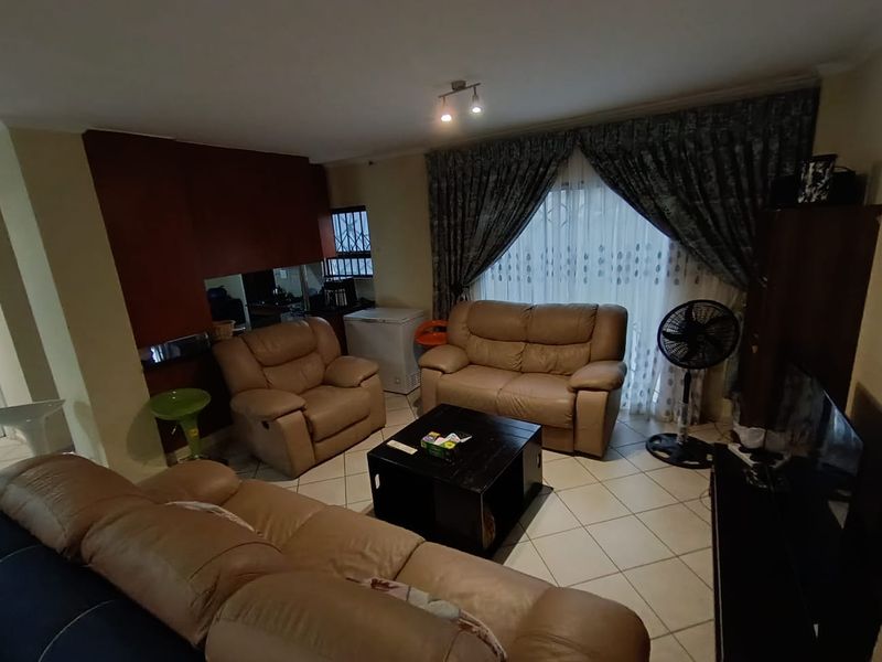 A living room featuring tiled flooring and a sliding glass door with curtains, including a built-in bar area.