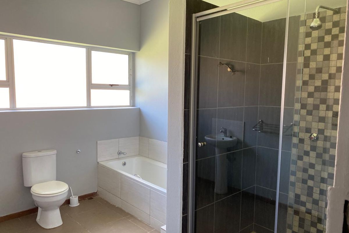 A functional bathroom featuring a built-in bathtub, a separate glass-enclosed shower with mosaic tile accents, a pedestal basin, and a standard toilet.