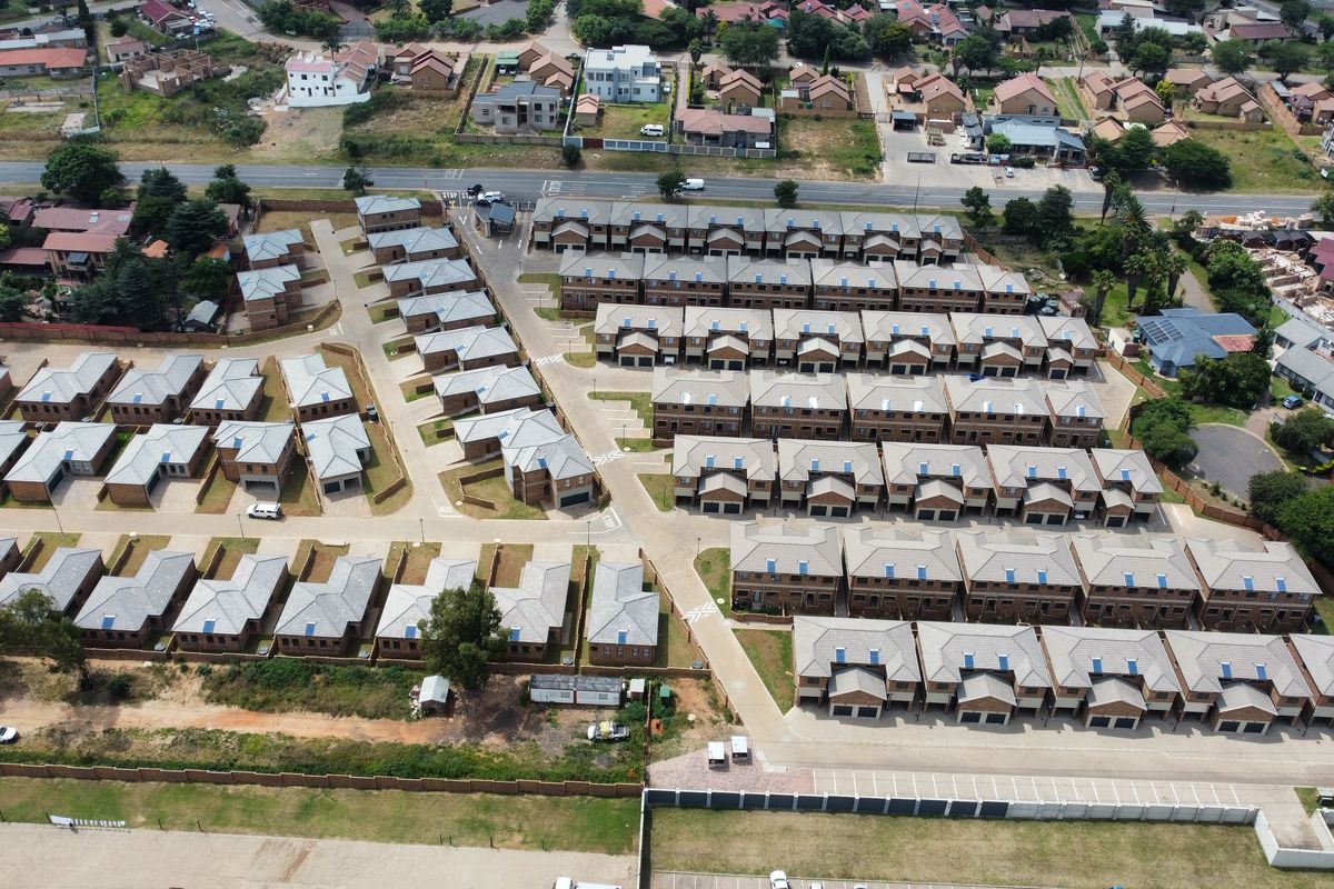 An aerial view of a modern residential housing estate featuring uniform detached and semi-detached homes with tiled roofs and paved access roads.