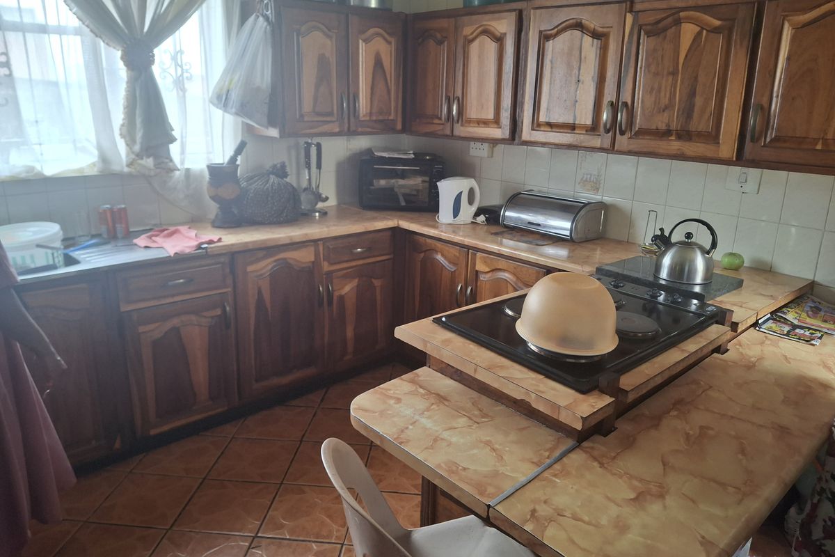 A functional kitchen featuring traditional wooden cabinetry, laminate countertops, and ceramic tile flooring, offering a classic layout with ample storage space.