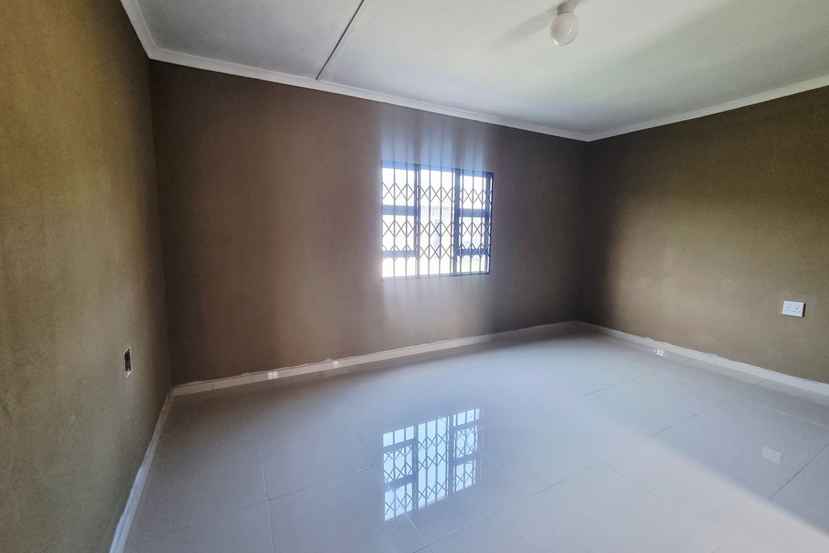 A vacant bedroom featuring neutral-toned walls, polished floor tiles, and a security gate on the window.