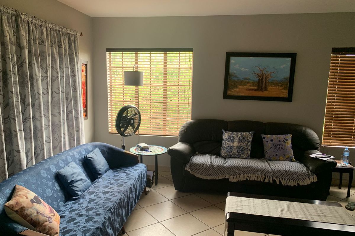 A comfortable living room featuring tiled flooring, recessed ceiling lighting, and large windows with fitted blinds, providing a bright and functional living space.