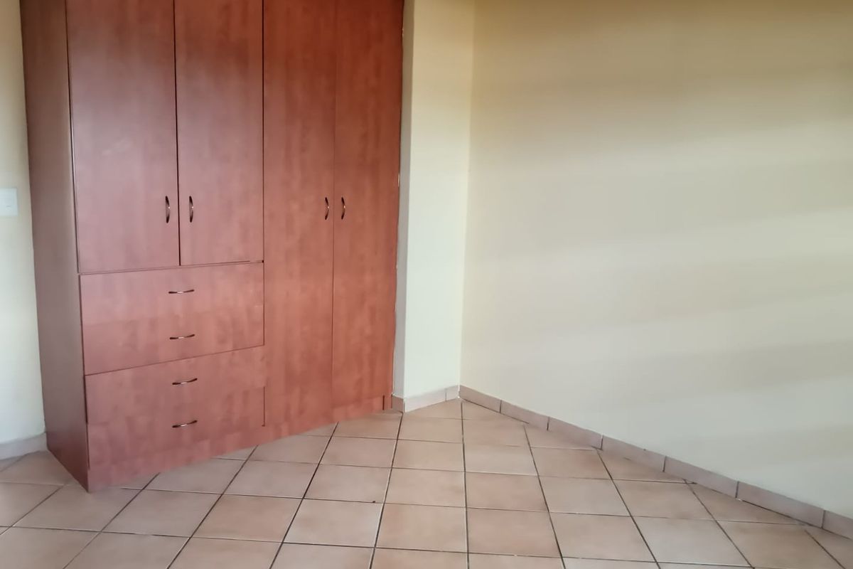 A bedroom featuring built-in wooden cabinetry and tiled flooring.
