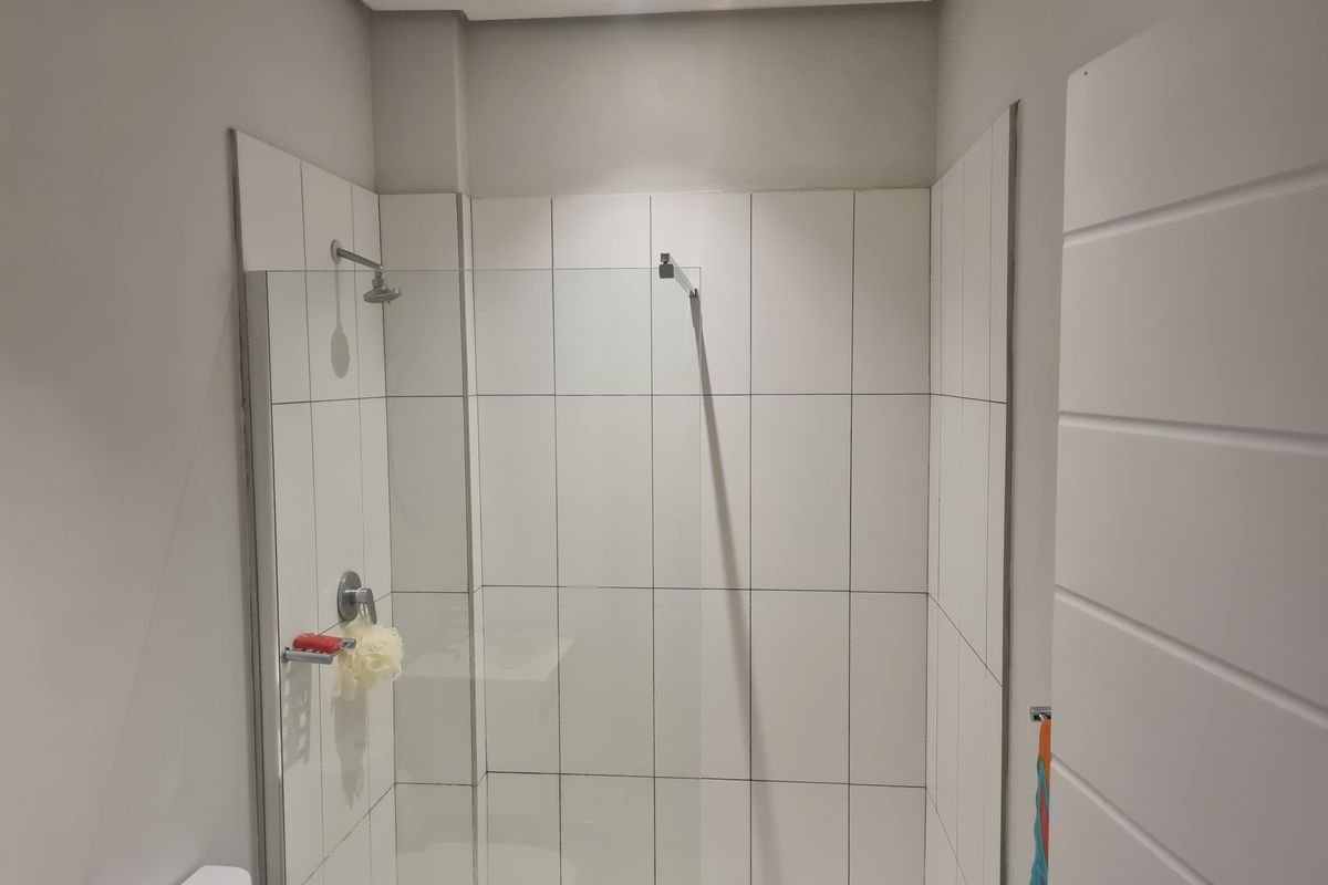 A clean, modern bathroom featuring a walk-in shower with a glass screen and white tiled walls.