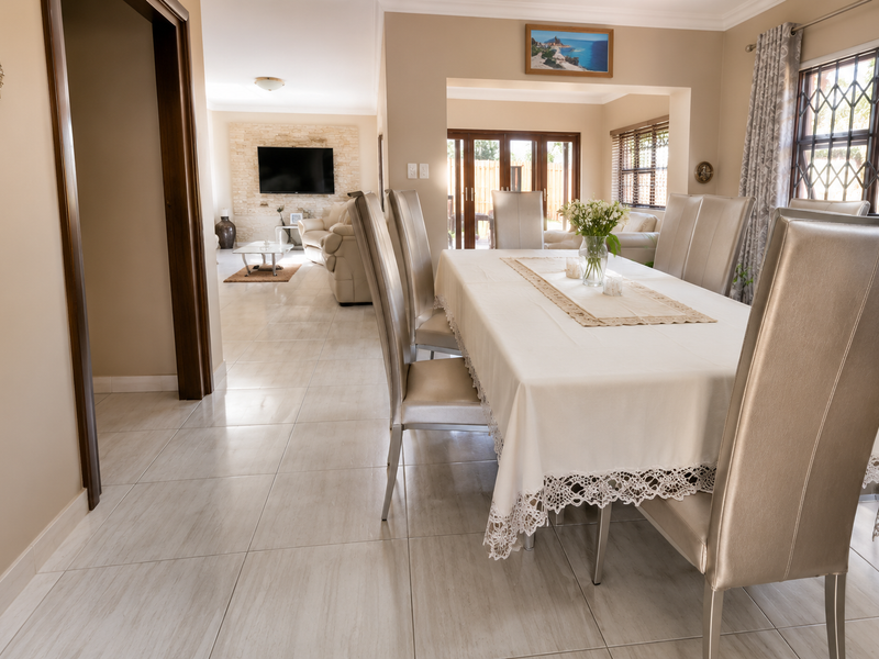 Spacious open-plan dining and living area featuring neutral tiled flooring, a stone feature wall, and sliding glass doors leading to the exterior.