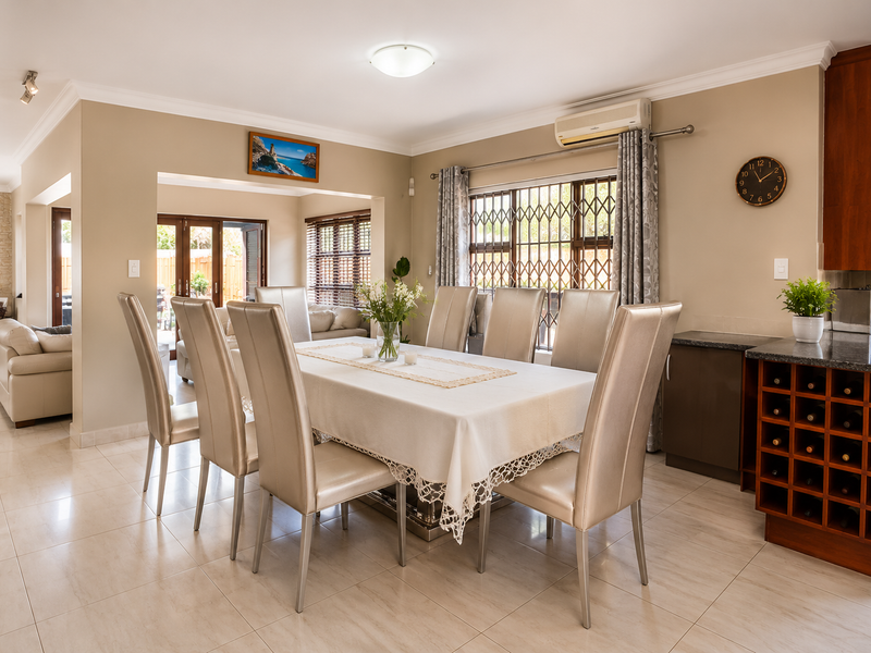 Spacious open-plan dining area featuring tiled floors, built-in wine storage, granite countertops, and direct access to the outdoor patio area.