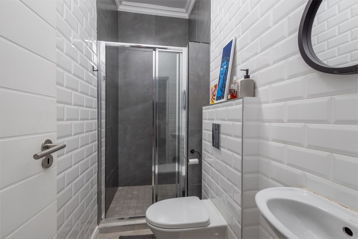 Modern bathroom featuring a glass shower enclosure, wall-hung toilet with concealed cistern, and white subway tile finishes.