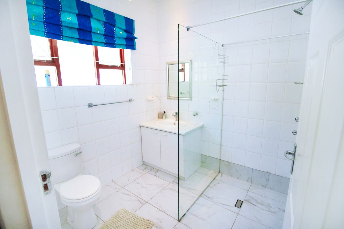 A functional bathroom featuring a walk-in glass shower, white vanity cabinet with integrated basin, and tiled flooring.