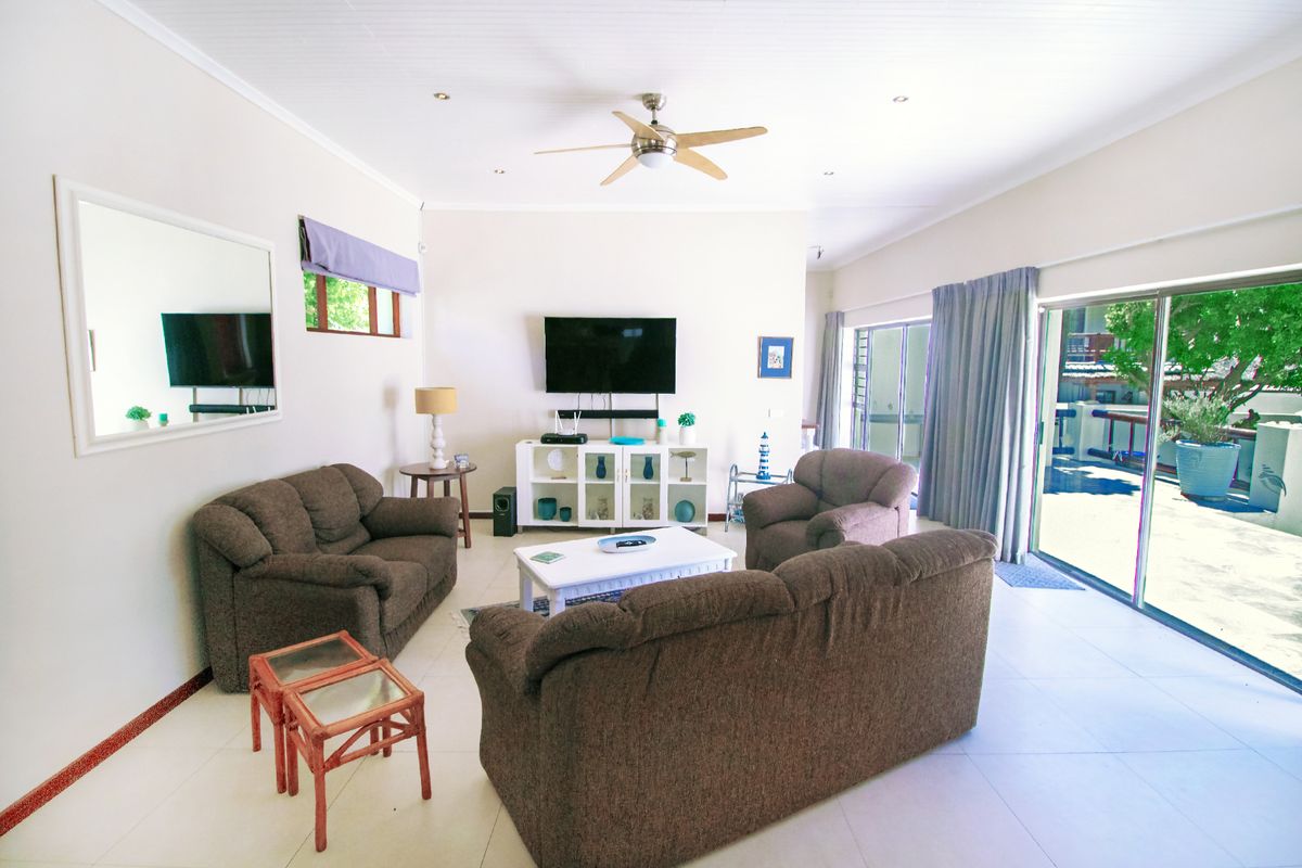 Spacious living room featuring tiled flooring, a ceiling fan, and large sliding glass doors providing direct access to the outdoor patio area.