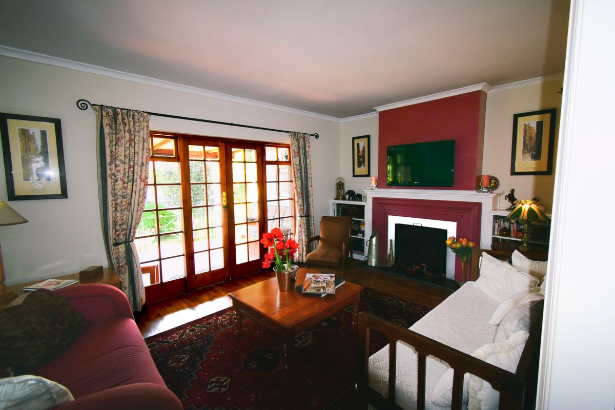 Cozy living room featuring a prominent fireplace, hardwood flooring, and timber-framed glass doors providing direct access to the outdoor patio area.