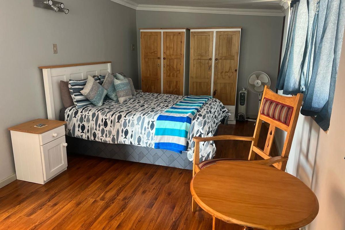 A bedroom featuring laminate flooring, built-in wooden wardrobes, and coving detail, providing a functional and comfortable sleeping space.
