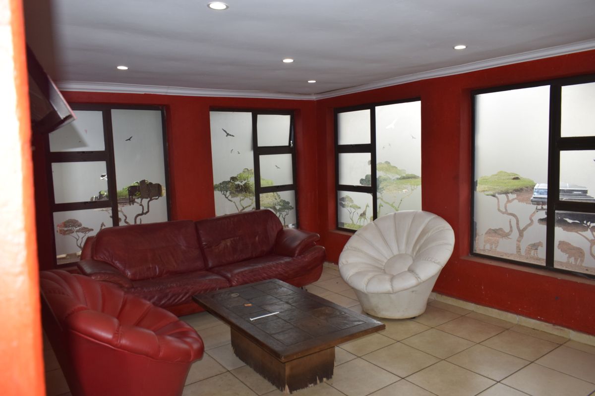 A living room featuring red walls, ceramic tiled flooring, and large aluminium-framed windows with decorative nature-themed decals.