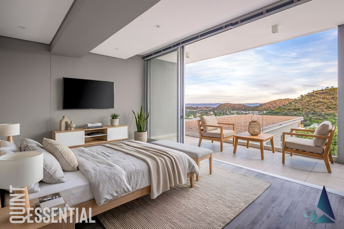 Modern bedroom featuring large sliding glass doors that open onto a private balcony with scenic mountain views.