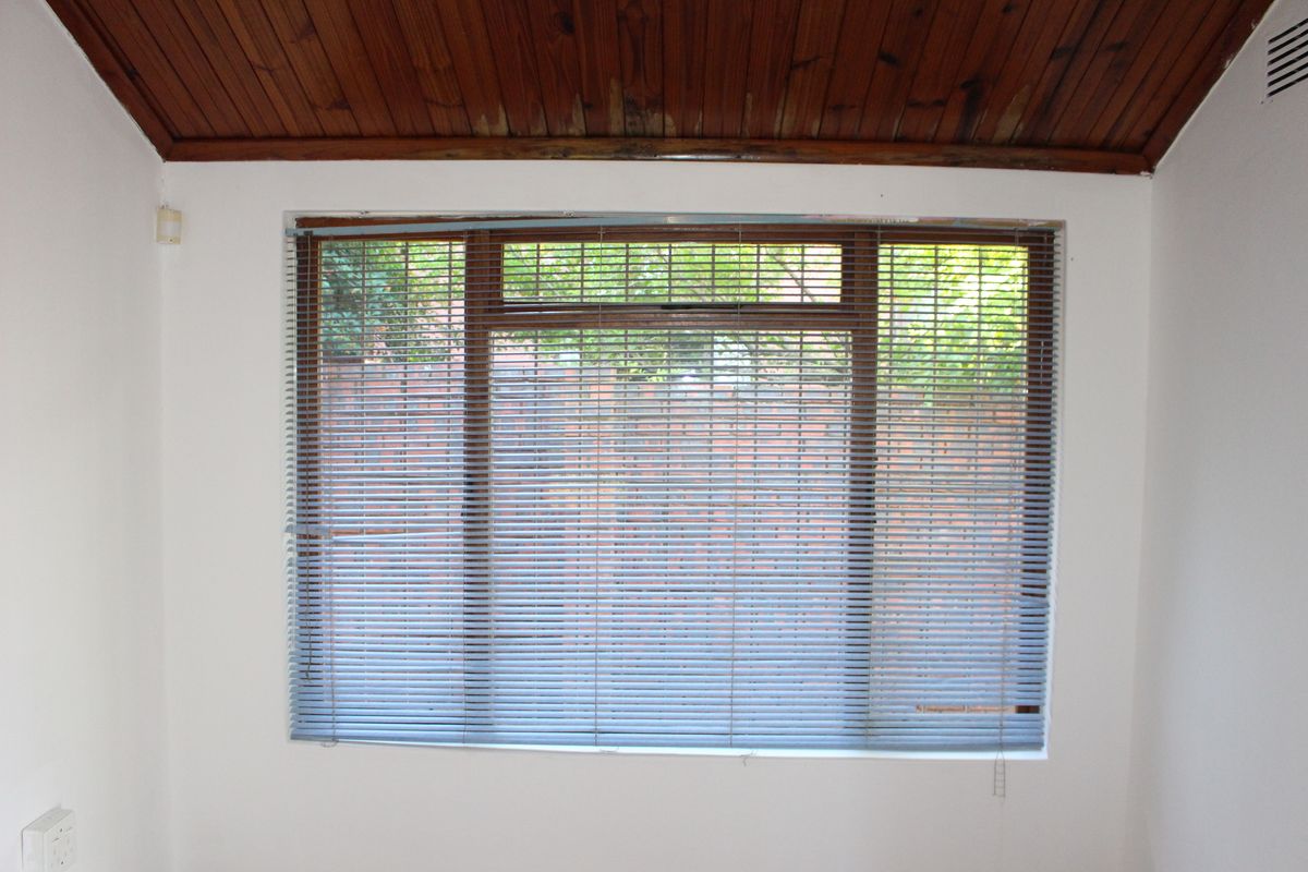 A vacant bedroom featuring a timber tongue and groove ceiling with visible water damage and an aluminium window frame.