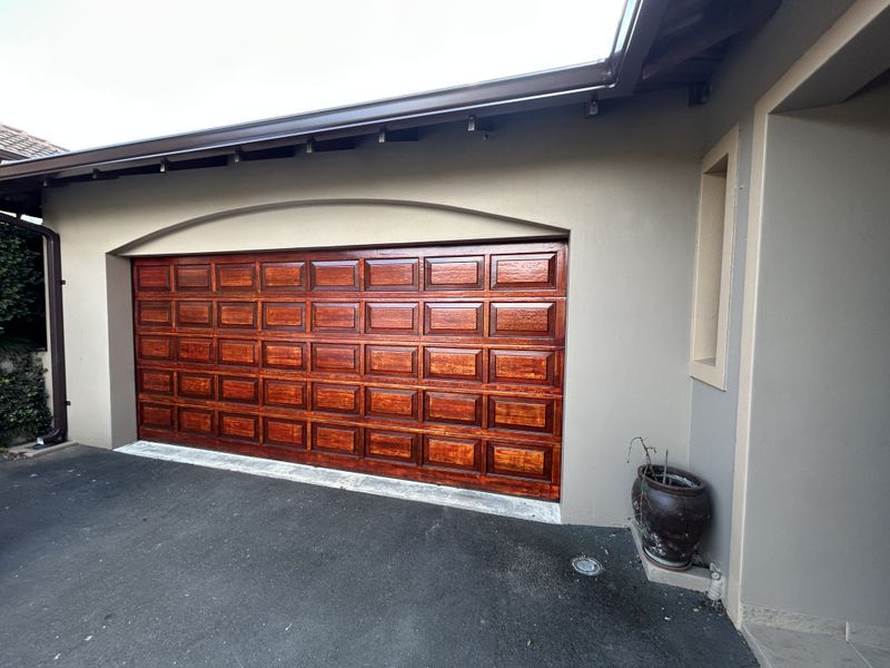 A well-maintained double garage featuring a polished wooden sectional door and a clean asphalt driveway approach.