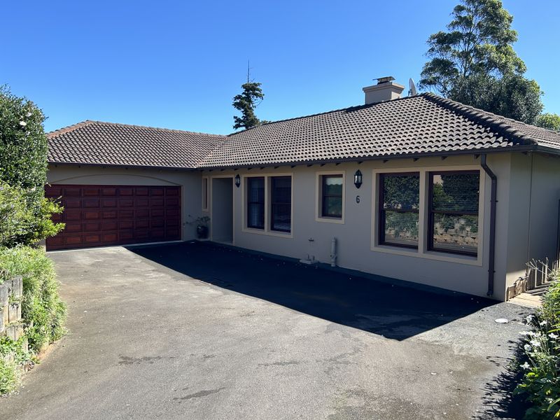 Front elevation of a single-story house featuring a tiled roof, asphalt driveway, and a double garage.