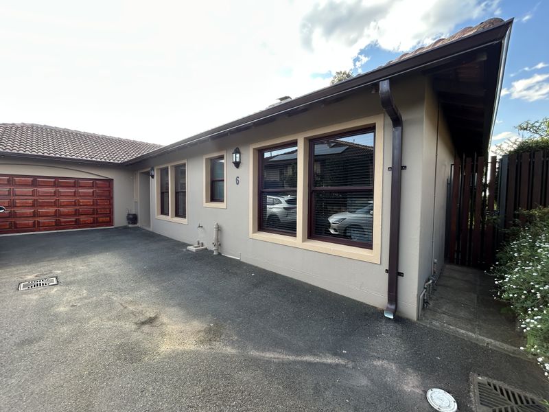 Front exterior view of the property featuring a paved driveway, tiled roof, and a secure garage entrance.