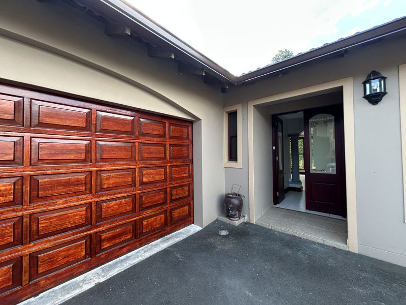 Front entrance area featuring a polished wooden sectional garage door, tiled porch, and a classic timber front door with glass detailing.