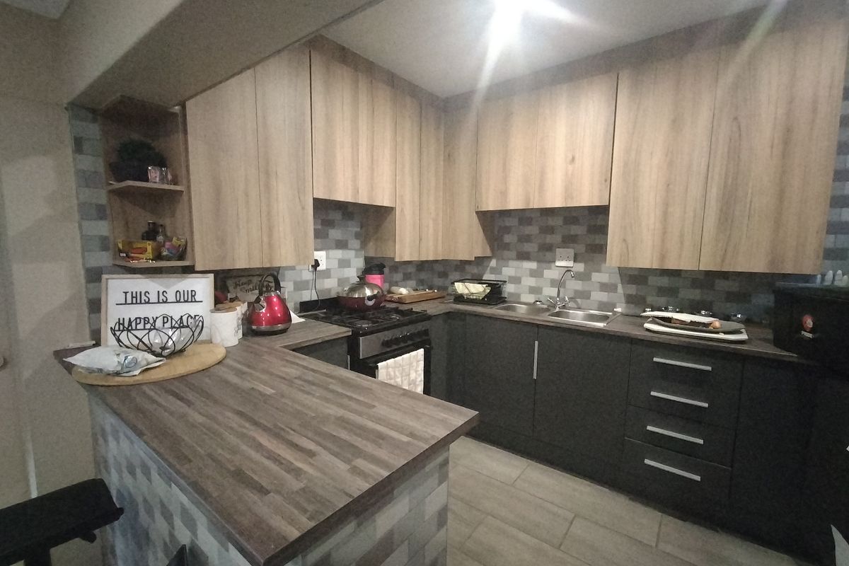 Modern kitchen featuring two-tone cabinetry, laminate countertops, a breakfast bar, gas stove, and a tiled backsplash.