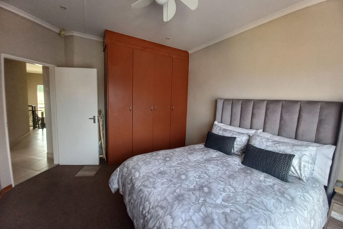A bedroom featuring built-in wooden cupboards, a ceiling fan, and neutral wall finishes, providing a functional and comfortable sleeping space.