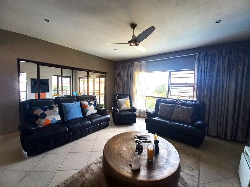 Spacious living room featuring tiled flooring, a ceiling fan, recessed lighting, and large windows providing natural light and access to the exterior.