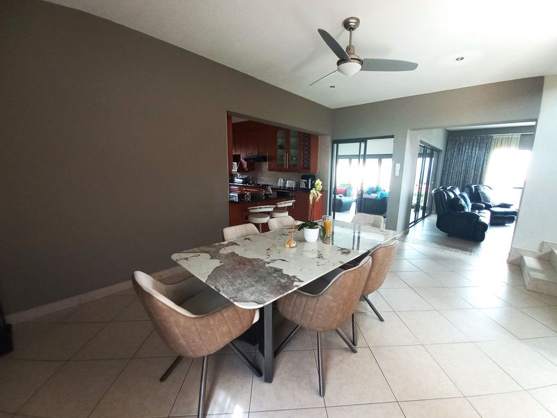 Open plan dining area featuring tiled flooring and recessed lighting, seamlessly connecting to the kitchen and adjacent living space with sliding door access.