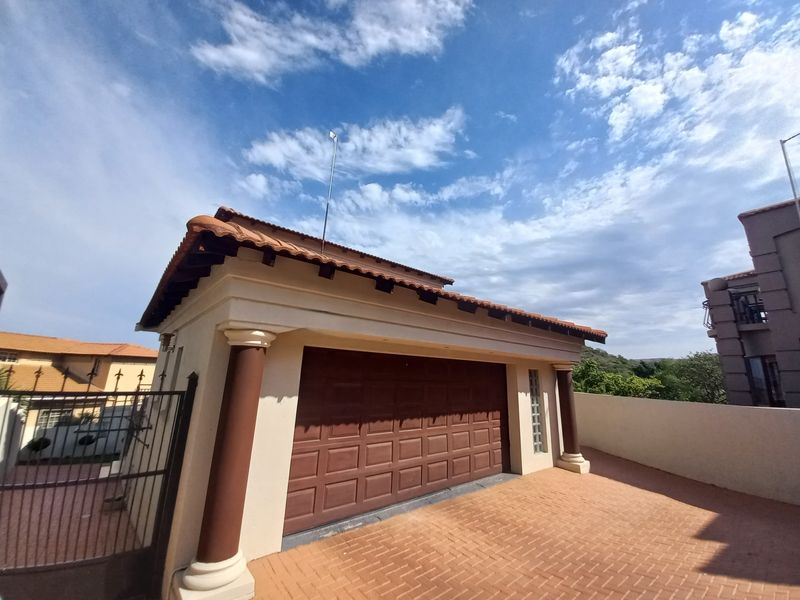 A well-maintained detached garage featuring a tiled roof, decorative columns, and a paved driveway entrance.